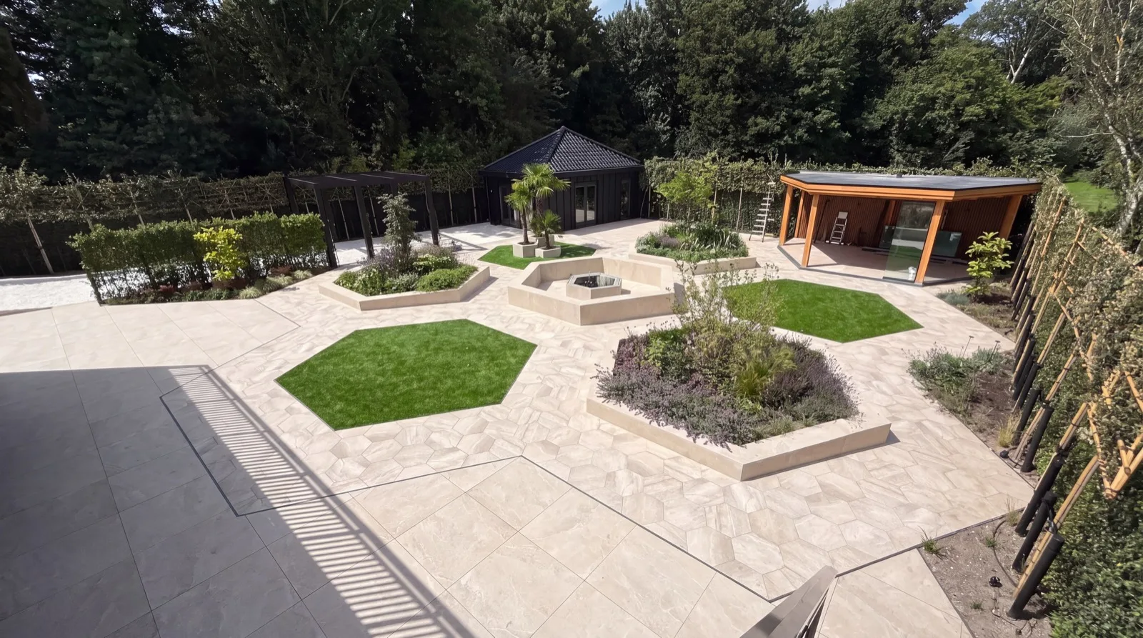 Na: opgeleverde tuin met zeshoekige plantvakken en zwart tuinhuis
