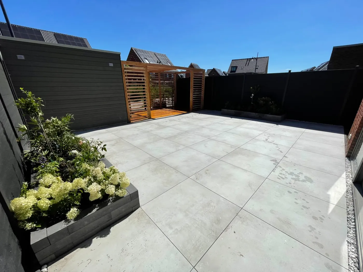 Terras van grijze tegels met plantenbak